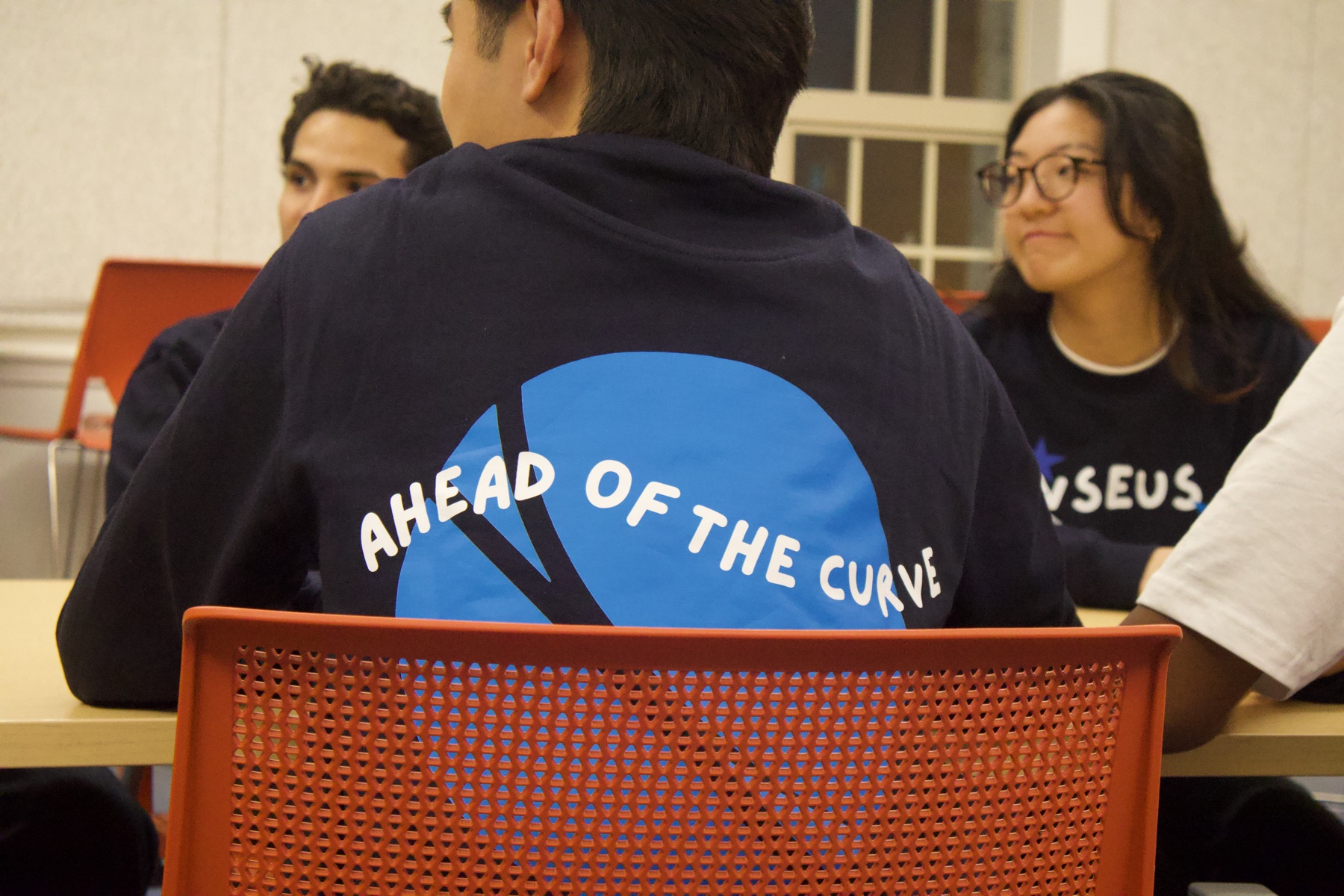 Back of a navy VSEUS sweater printed with "Ahead of the Curve"