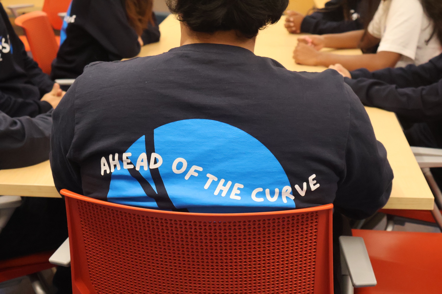 Back of a navy VSEUS sweater with the large "Ahead of the Curve" print