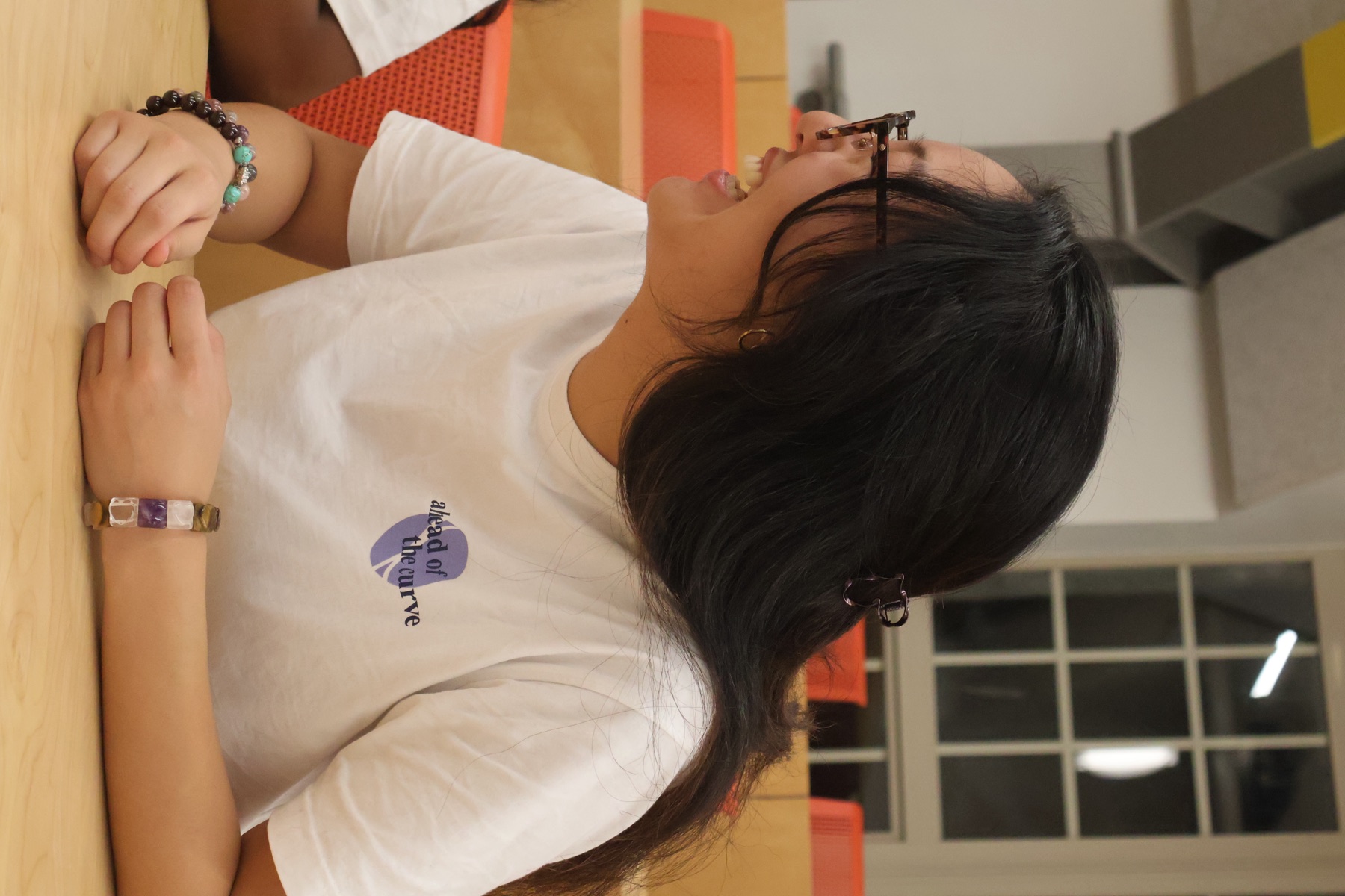 A student laughing in a white VSEUS tee with the "ahead of the curve" print